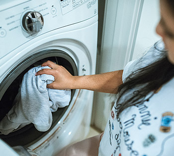 Customer loading laundry into a washing machine